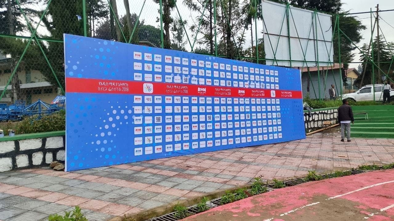 Wide blue step-and-repeat press wall covered in sponsor logos for an Addis Media Network festival
