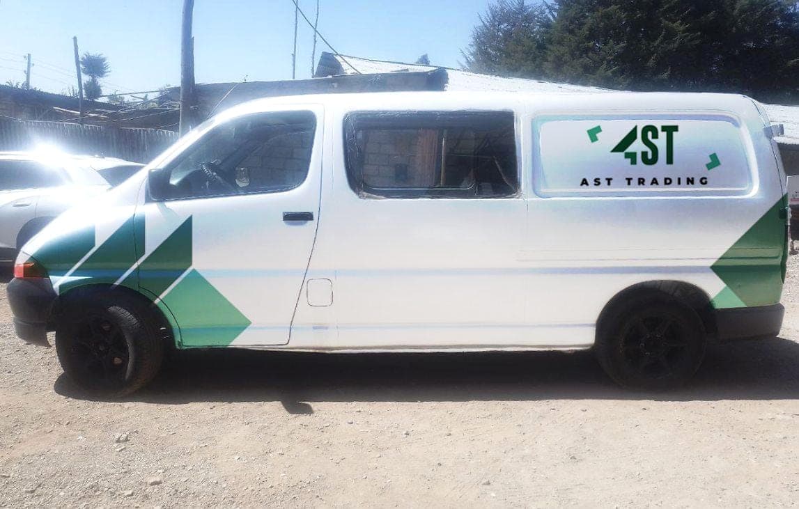 White minibus with the AST Trading logo on the rear window and a green chevron pattern running along the lower body
