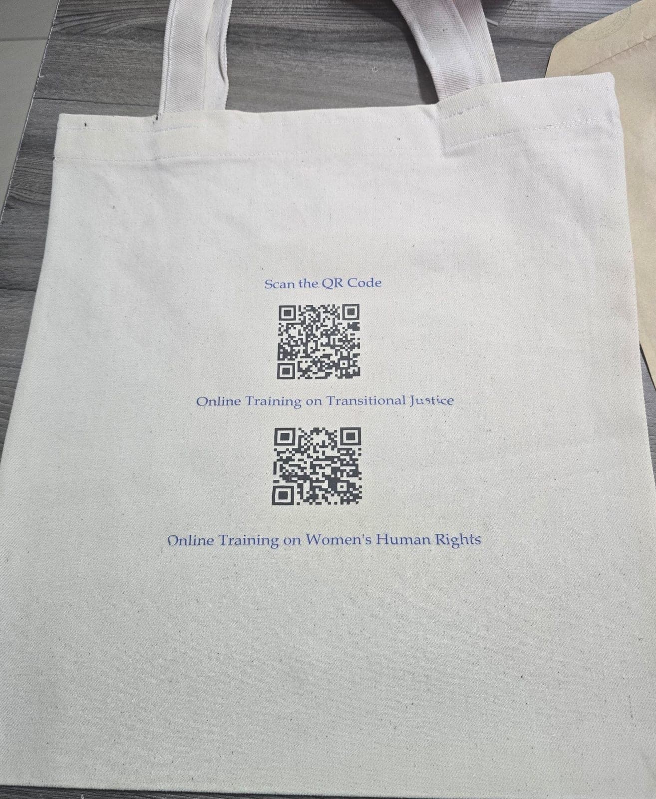 Reverse of the canvas tote bag printed with two QR codes linking to online training
