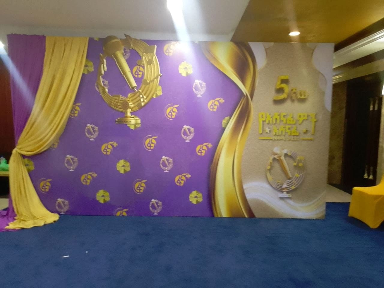 Purple and gold awards backdrop with a raised gold microphone motif and dimensional lettering for the Fana Artists Award