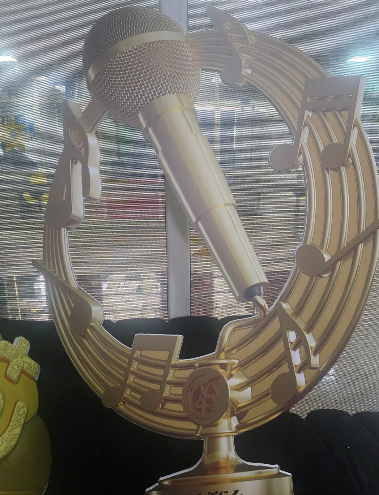 Oversized contour-cut gold prop of a microphone framed by a stave of musical notes, built for an awards stage
