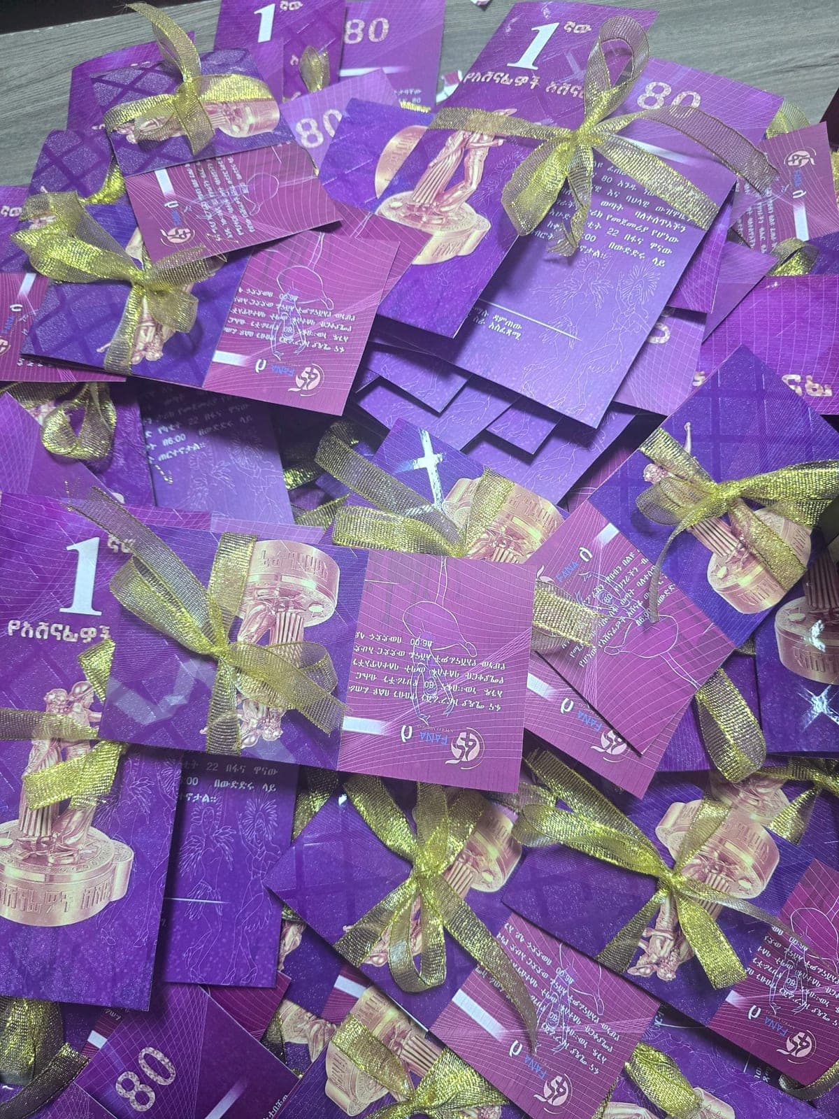 Close detail of the purple foil anniversary invitation cards and their gold ribbon ties
