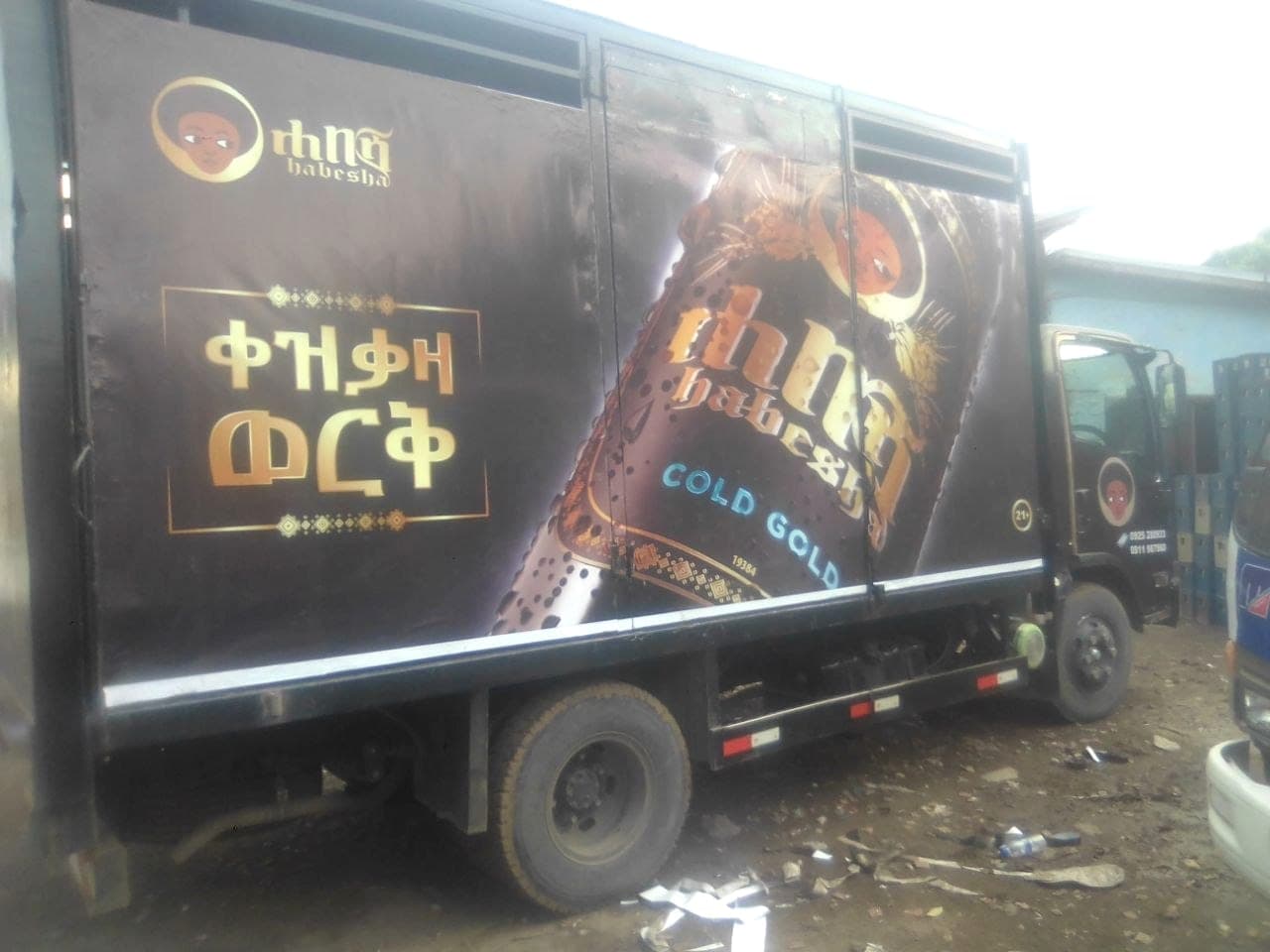 Distribution truck wrapped in the dark Habesha Cold Gold livery, the bottle artwork running across the full side panel