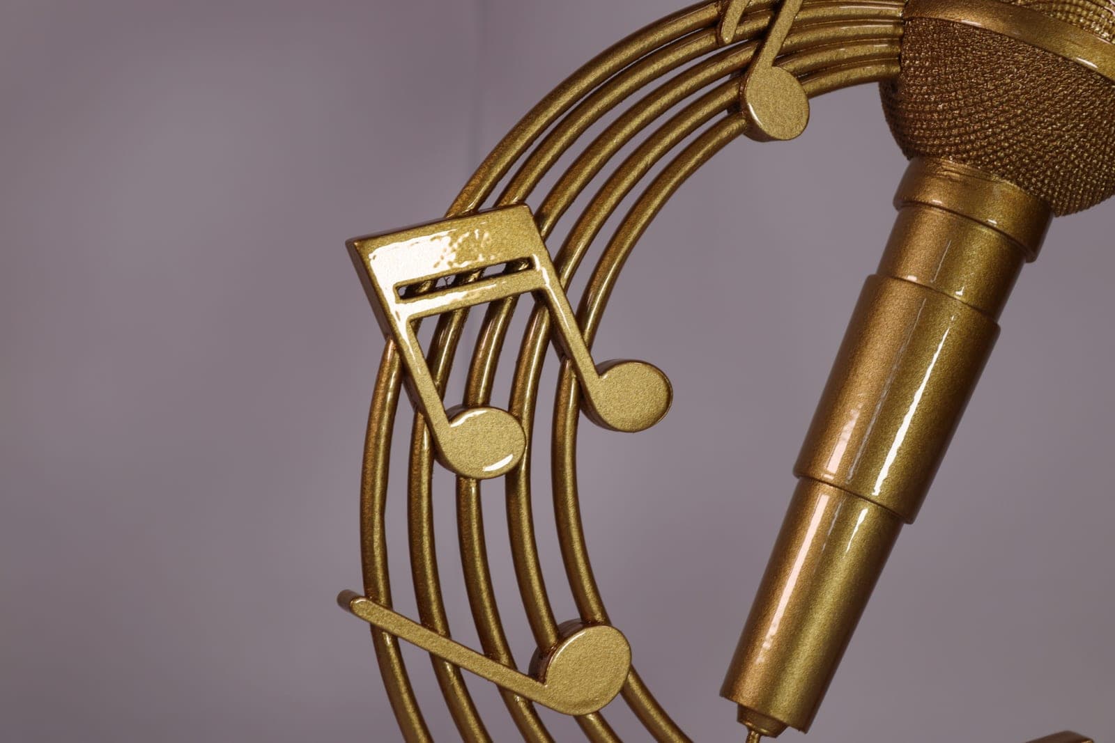 Close detail of the gold trophy showing the cast musical notes crossing the stave beside the microphone body