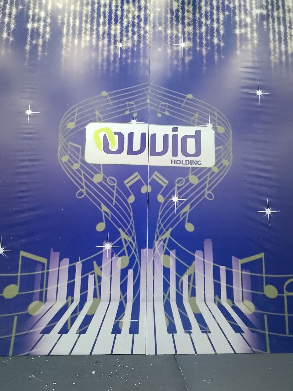 Blue and gold stage backdrop for Ovid Holding, printed with piano keys, musical notes and falling lights