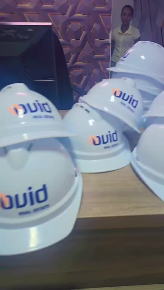 White safety helmets printed with the Ovid Real Estate logo, lined up in the workshop