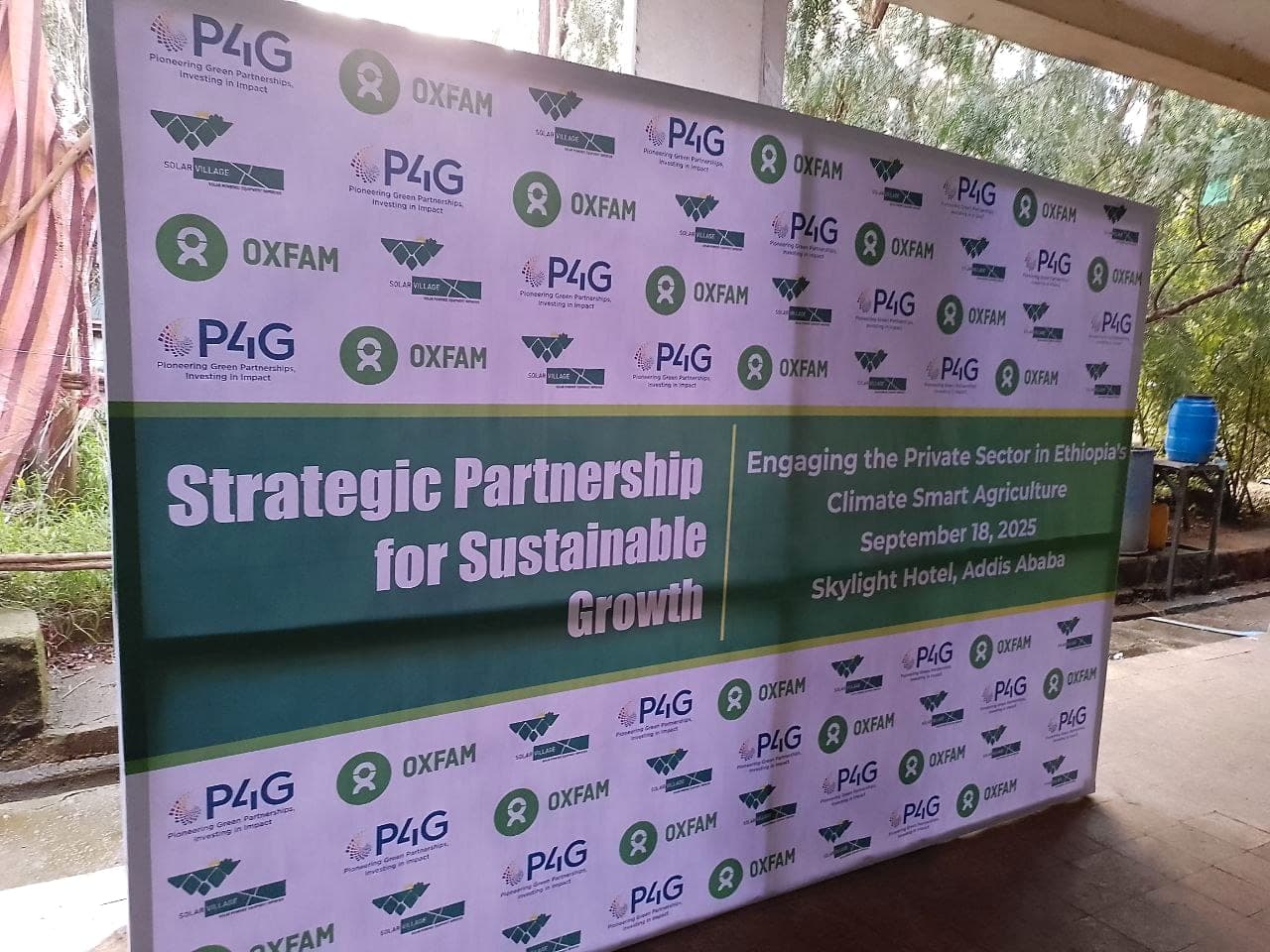 Green and white step-and-repeat press wall for a sustainable growth partnership event, repeating the Oxfam, P4G and Solar Village logos